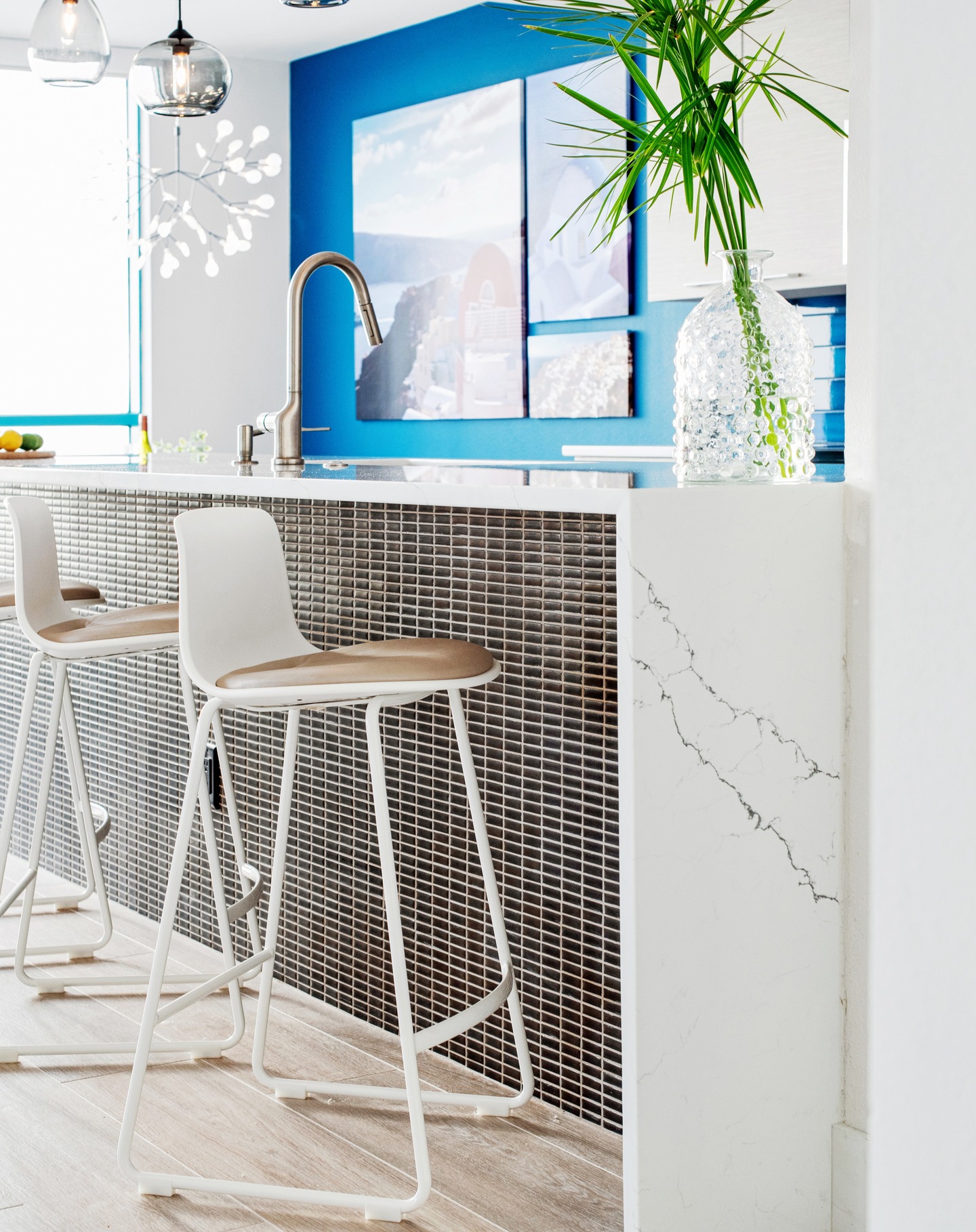 Not all kitchen islands are created equal.
Some just sit there—and some become the wow moment of the whole space. We want the island to be a magnet where people naturally gather, pull up a stool, sip a glass of wine... maybe even check an email or two. 
In our Castaway Oceanfront Getaway project, the island had to do it all—be the workhorse and the showstopper. Here’s how we made that happen:
✔️ @annsacks_hospitality metallic mosaic tile on the front—it’s textural, durable, and can take the occasional kick.
✔️ Waterfall quartz countertop for crisp contrast and clean structure.
✔️ Treefrog veneer by @chemetal.treefrog.interiorarts on the working side—sustainably sourced and warm like real wood, but wears like a pro.
We paired it with the Enea Lottus stools by @coalesse—white molded frames and the softest taupe leather. Comfortable, sculptural, and quiet enough to let the island shine.
Handblown smoky glass pendants by @hennepinmade, each slightly different and hung at varied heights to soften the strong lines below and add an artisanal touch.
We always use 2600K bulbs here—a soft, candlelit glow that’s flattering at any hour.
This island doesn’t just look good—it holds the room, anchors the flow, and quietly makes the whole space work. 
We believe that’s good design.
Design by @adinahalldesign
Photography by @christinastrongphotography
#adinahalldesign #interiordesigner #chicagobuilder #chicagodesigner #chicagorealestate #chicagointeriordesigner #chicagoarchitect #kitchendesigner #kitchenislanddesign #openconceptkitchen #modernkitchen #kitchenlighting #kitcheninspo #luxurykitchen #kitchendetails #kitchenstyling #kitchengoals #designmatters