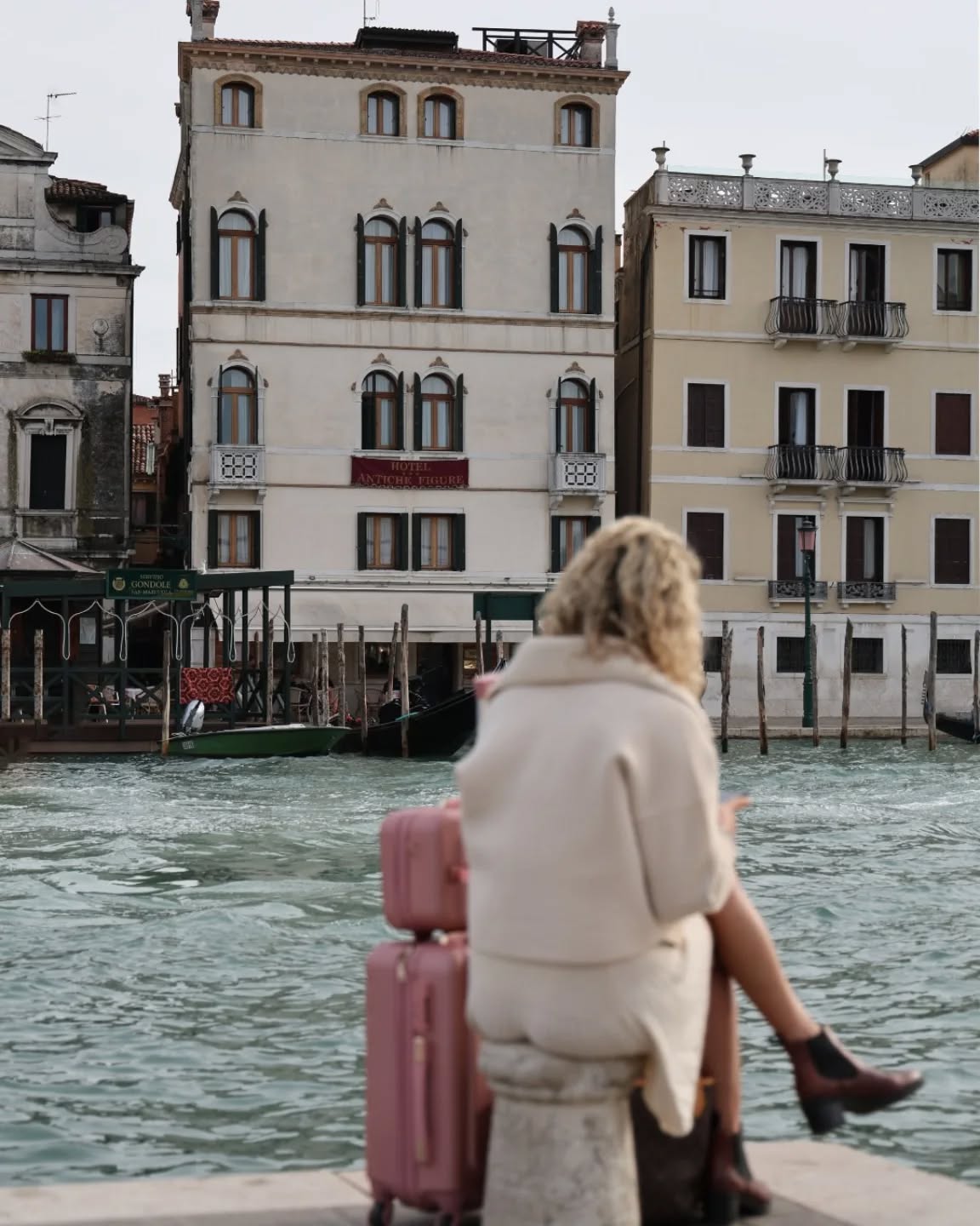 È appena arrivata a Venezia.
I bagagli accanto, il Canal Grande davanti.
Si ferma un istante, respira, guarda la città riflettersi sull’acqua.
Dall’altra parte la attende il suo hotel.
Tra poco un taxi la condurrà oltre il canale, e quel primo attraversamento diventerà parte del viaggio: un piccolo rito d’ingresso nella città sospesa tra sogno e realtà.
Perché qui, anche l’arrivo è già un’emozione. ✨
She has just arrived in Venice.
Her luggage beside her, the Grand Canal in front of her.
She pauses for a moment, breathes, and watches the city reflect on the water.
On the other side, her hotel Antiche FIgure is waiting.
Soon a water taxi will take her across the canal, and that first crossing will become part of the journey: a small rite of passage into a city suspended between dream and reality.
Because here, even arriving is already an emotion. ✨